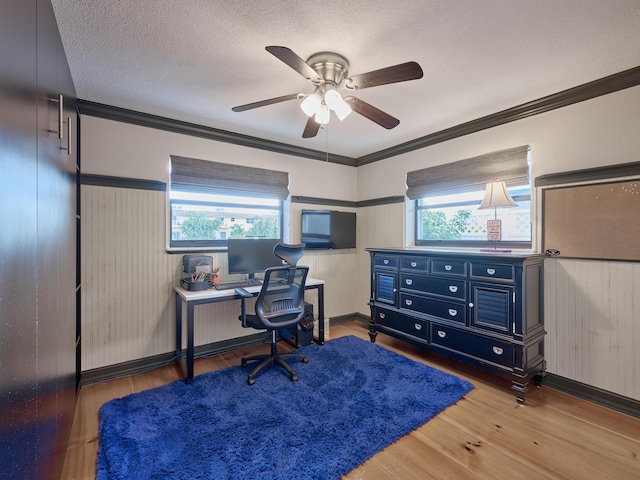 office area featuring plenty of natural light, a textured ceiling, ornamental molding, and wood finished floors