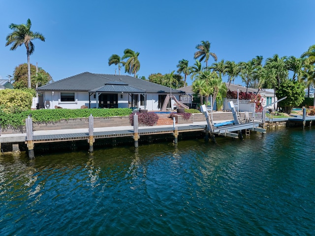 dock area featuring a water view, boat lift, and fence