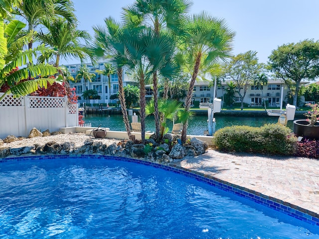 outdoor pool featuring a dock, a water view, and fence