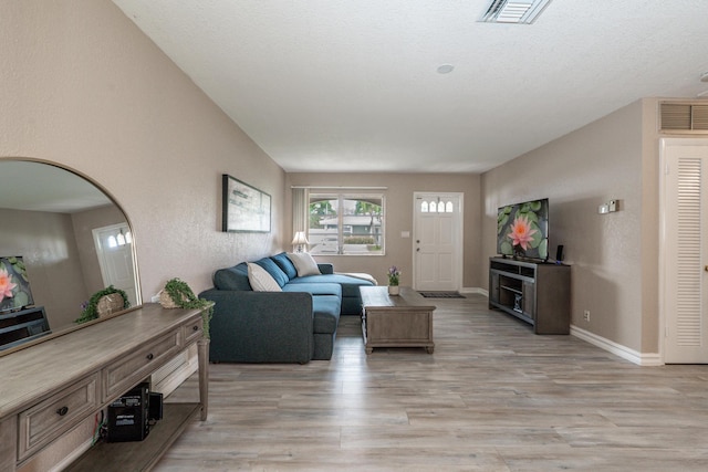 living room featuring light wood-style flooring, visible vents, arched walkways, and baseboards