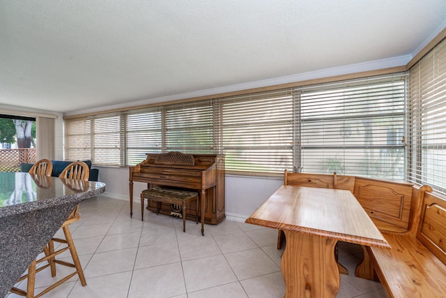 dining space with a textured ceiling, light tile patterned flooring, and baseboards