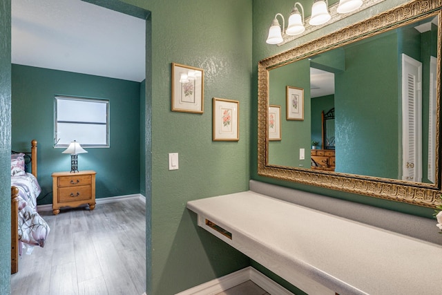 bathroom featuring a textured wall, baseboards, and wood finished floors