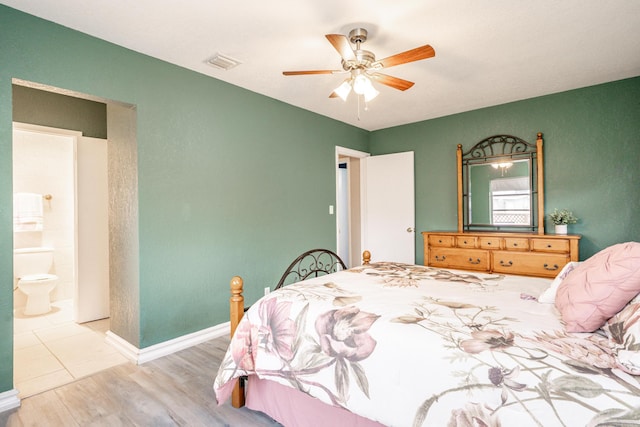 bedroom featuring visible vents, a ceiling fan, ensuite bath, wood finished floors, and baseboards