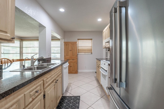 kitchen with high end refrigerator, dishwasher, light tile patterned flooring, a sink, and range with electric stovetop