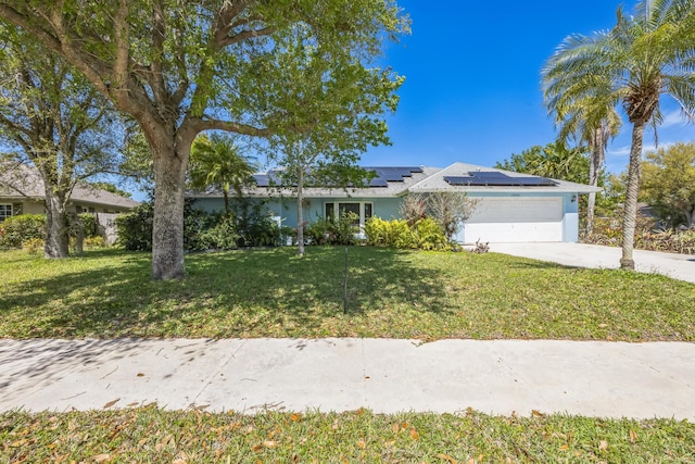 single story home with a garage, driveway, solar panels, a front yard, and stucco siding