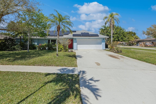 single story home with a garage, driveway, a front yard, and roof mounted solar panels