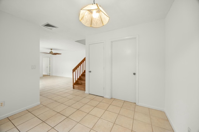 spare room featuring light tile patterned flooring, visible vents, ceiling fan, and stairs