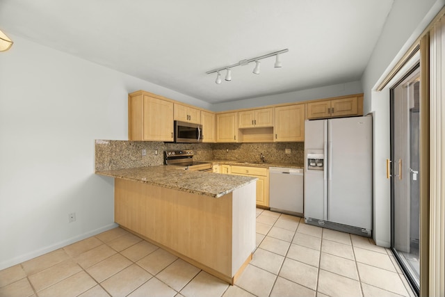 kitchen featuring light tile patterned floors, stainless steel appliances, a peninsula, decorative backsplash, and light brown cabinetry