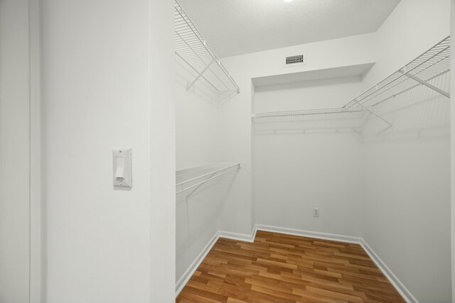 spacious closet featuring visible vents and wood finished floors