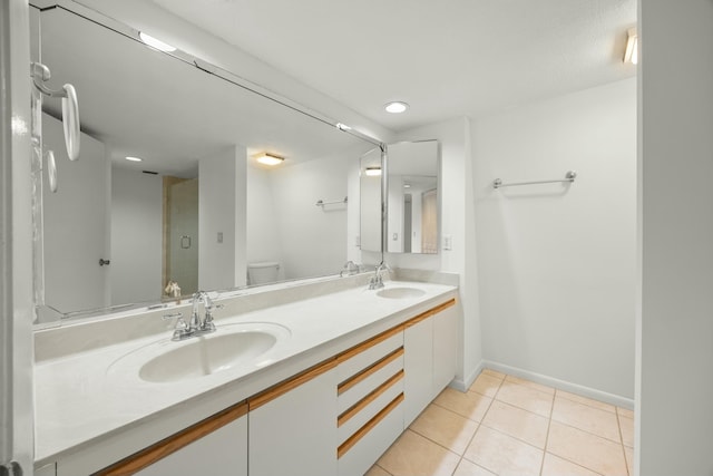 bathroom with toilet, double vanity, a sink, and tile patterned floors