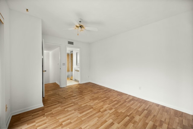 spare room featuring baseboards, a ceiling fan, visible vents, and light wood-style floors