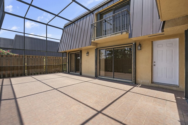 back of house featuring a balcony, a lanai, fence, a patio area, and stucco siding