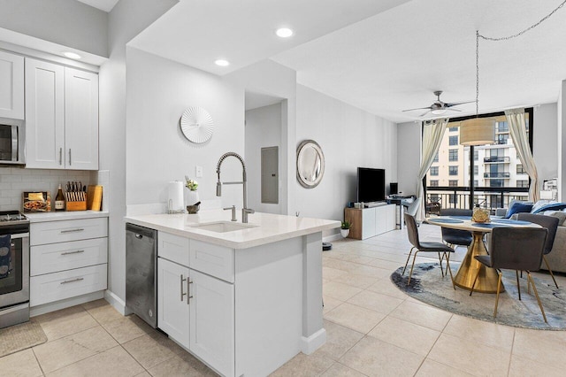 kitchen with tasteful backsplash, open floor plan, a peninsula, stainless steel appliances, and a sink