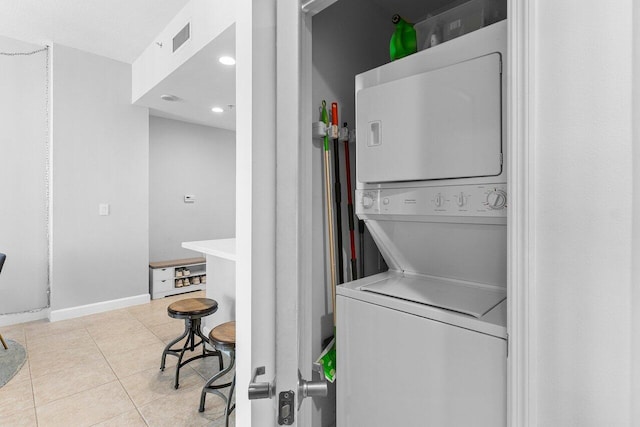 washroom featuring light tile patterned floors, baseboards, visible vents, and stacked washer / drying machine