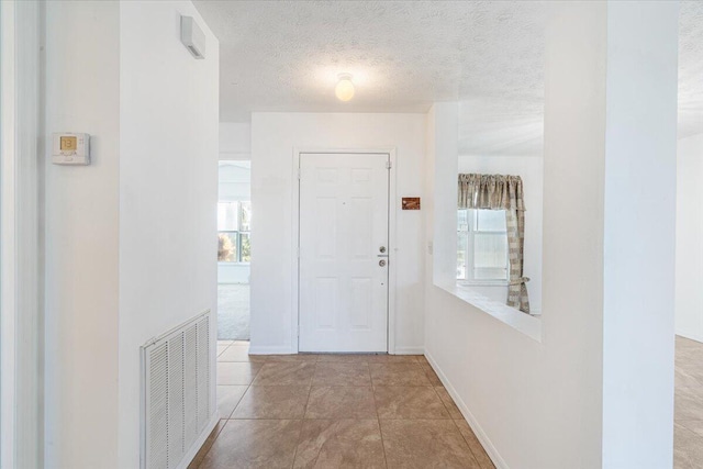 6625 Alheli Ct, Fort Pierce, FL 34951 - corridor with tile patterned flooring, visible vents, a textured ceiling, and baseboards