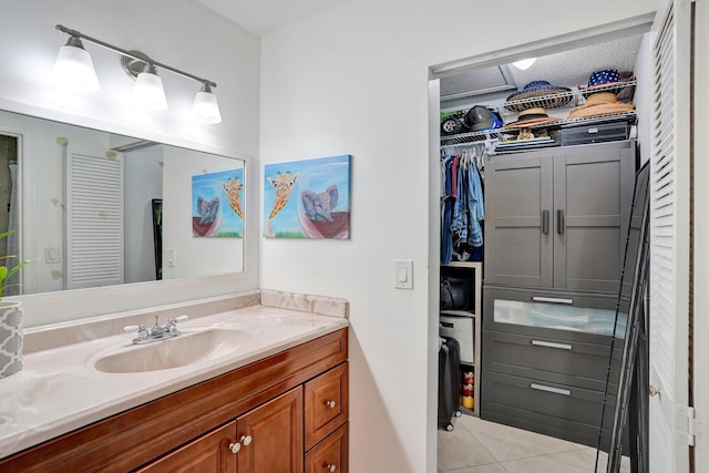 bathroom featuring tile patterned flooring, a spacious closet, and vanity