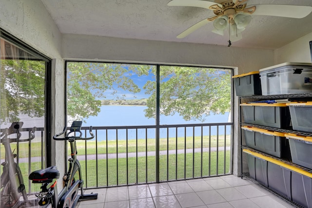 unfurnished sunroom featuring a water view and a ceiling fan