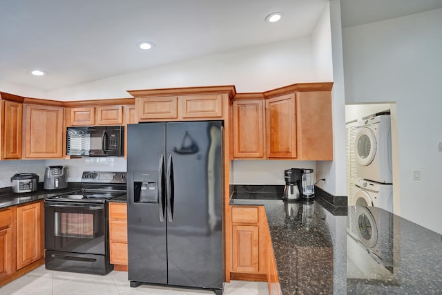 kitchen with lofted ceiling, stacked washer and dryer, recessed lighting, dark stone countertops, and black appliances