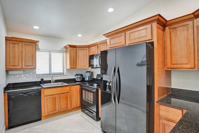 kitchen with dark stone countertops, light tile patterned floors, lofted ceiling, a sink, and black appliances