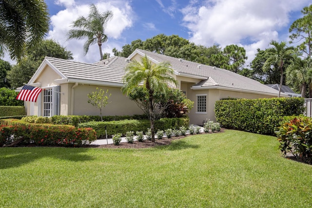 exterior space with stucco siding, a tile roof, and a yard