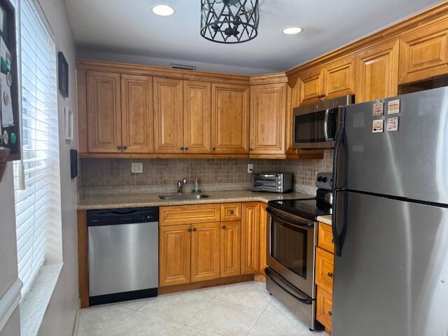 kitchen with decorative backsplash, stainless steel appliances, a sink, and light countertops