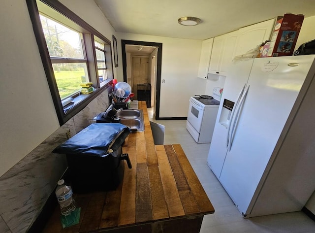 kitchen with white appliances, a sink, white cabinetry, and baseboards