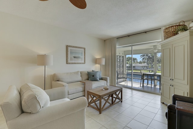 living room featuring ceiling fan, a textured ceiling, and light tile patterned floors