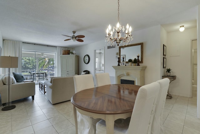 dining room featuring a fireplace, ceiling fan with notable chandelier, and light tile patterned flooring