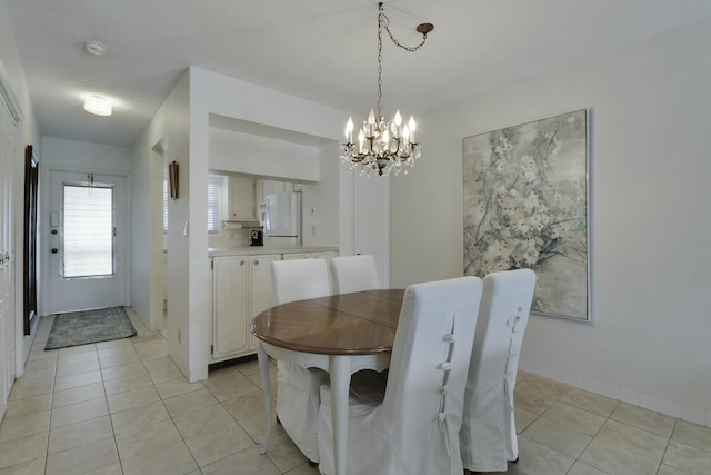 dining area with a chandelier, light tile patterned floors, and baseboards