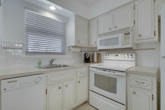 kitchen featuring tasteful backsplash, light countertops, white cabinets, a sink, and white appliances