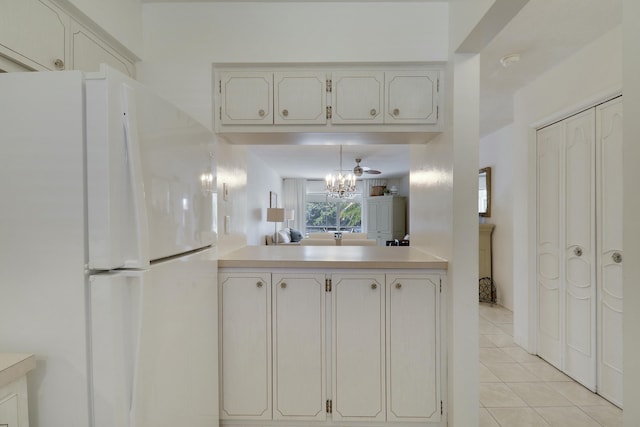 kitchen featuring light countertops, light tile patterned flooring, freestanding refrigerator, and a notable chandelier