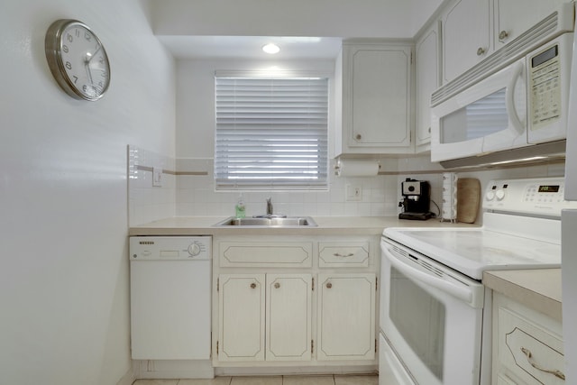 kitchen with light countertops, white appliances, backsplash, and a sink