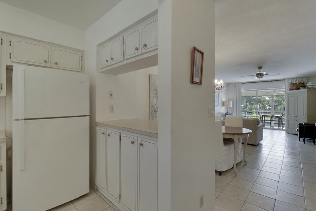 kitchen with freestanding refrigerator, white cabinetry, ceiling fan, and light tile patterned floors