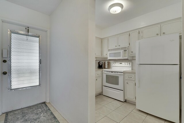 kitchen featuring light tile patterned floors, light countertops, white appliances, and white cabinets