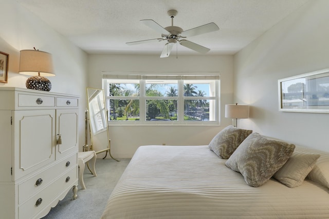 bedroom featuring multiple windows, a ceiling fan, a textured ceiling, and light colored carpet