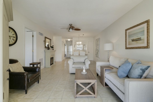 living area featuring ceiling fan with notable chandelier, visible vents, a fireplace, and light tile patterned flooring