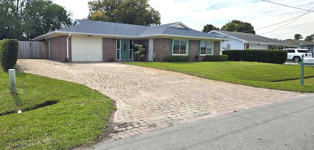 single story home featuring decorative driveway, brick siding, an attached garage, fence, and a front lawn