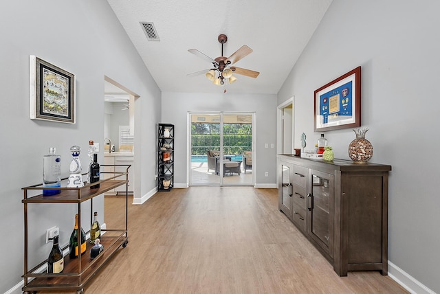 interior space featuring lofted ceiling, light wood-style flooring, baseboards, and ceiling fan