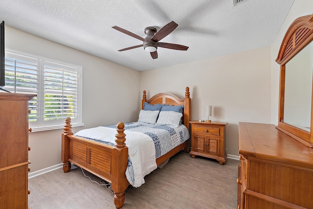 bedroom with light wood-style floors, a ceiling fan, and a textured ceiling