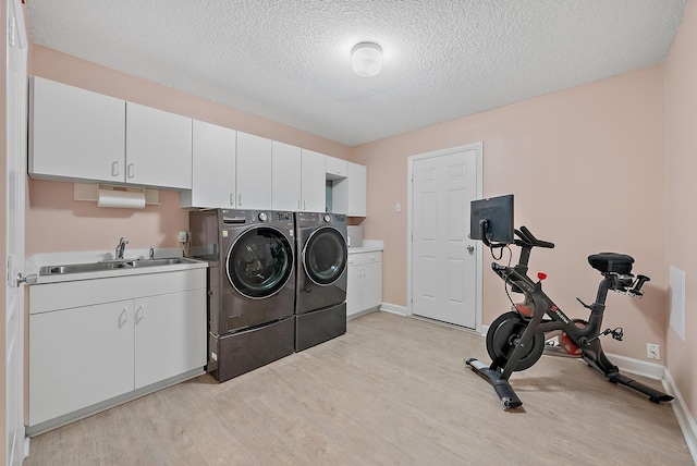 laundry area with baseboards, cabinet space, a sink, light wood-style floors, and independent washer and dryer