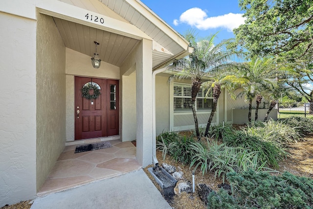 entrance to property featuring stucco siding and fence