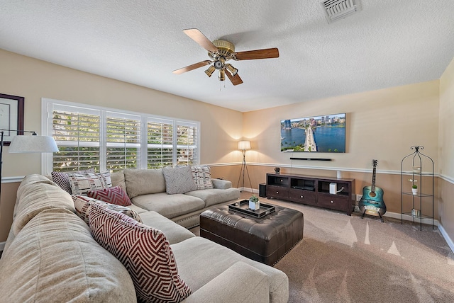 living room featuring visible vents, a textured ceiling, carpet flooring, baseboards, and ceiling fan