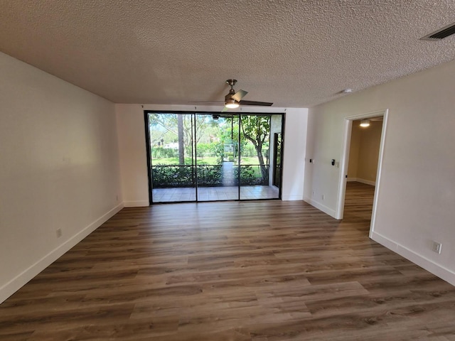 spare room with visible vents, a textured ceiling, baseboards, and wood finished floors