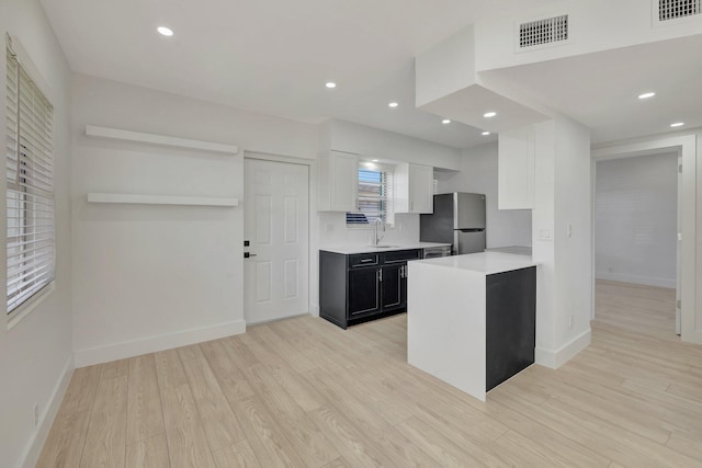 kitchen with visible vents, light countertops, dark cabinets, and freestanding refrigerator