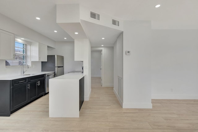 kitchen with light countertops, appliances with stainless steel finishes, a sink, and visible vents