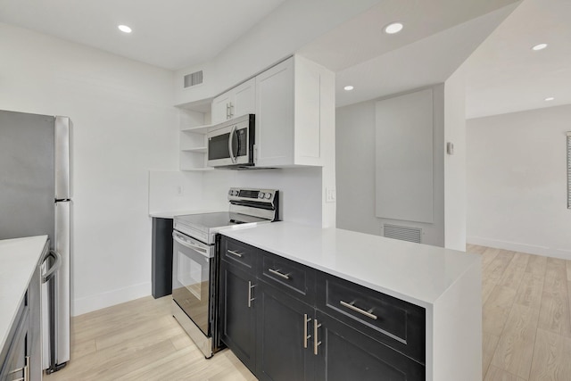 kitchen with visible vents, light wood-style flooring, appliances with stainless steel finishes, dark cabinetry, and open shelves