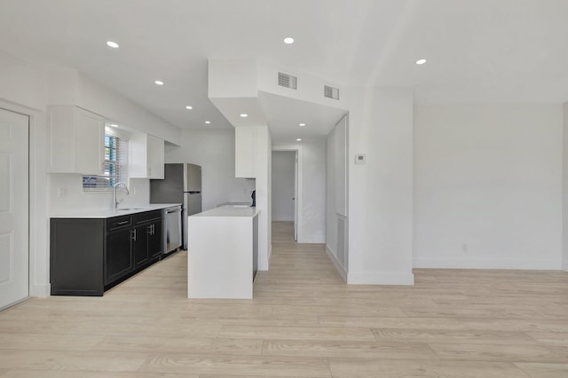 kitchen with light countertops, visible vents, appliances with stainless steel finishes, white cabinets, and a sink