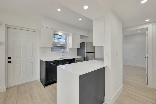 kitchen featuring light wood-style floors, white cabinetry, appliances with stainless steel finishes, and a sink