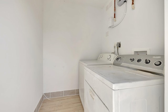 laundry room with laundry area, light wood-type flooring, washing machine and clothes dryer, and baseboards