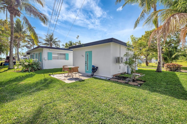 rear view of property with a yard, a patio, and stucco siding